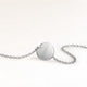 Baksidan av ett runt silverhalsband med personlig gravyr av ett datum