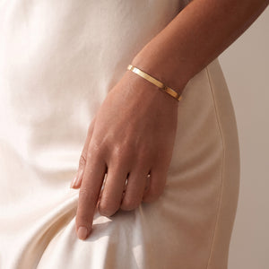Modell med personligt bangle guldarmband med plats för gravyr av text eller koordinater