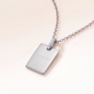 Personligt fyrkantigt silverhalsband med vita zirkoner sett från sidan, med gravyr av årtal och hjärta på framsidan