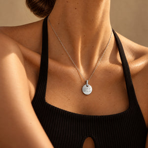 Modell i svart ribbstickad halterneck-topp med personligt runt silverhalsband med vita zirkonia, graverat med initialer och datum – plats för text, koordinater eller handstil på baksidan