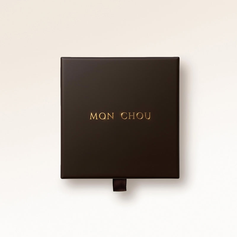 Mon Chous exklusiva presentbox i mörkbrun med guldlogga, gratis presentinslagning till personliga halsband och armband med gravyr.