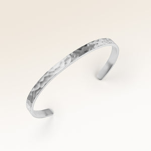 Närbild av minimalistiskt bangle armband i silver med vågig yta och plats för personlig gravyr