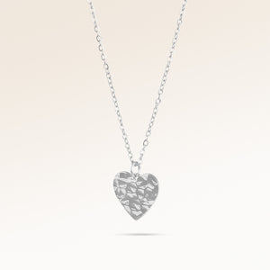 Hjärtformat silverhalsband med vågig yta sett från sidan, plats för gravyr baktill