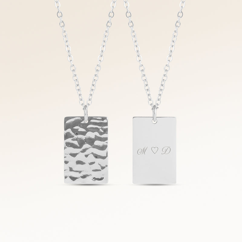 Personligt fyrkantigt silverhalsband med vågig yta och plats för gravyr av text, koordinater eller handstil på baksidan